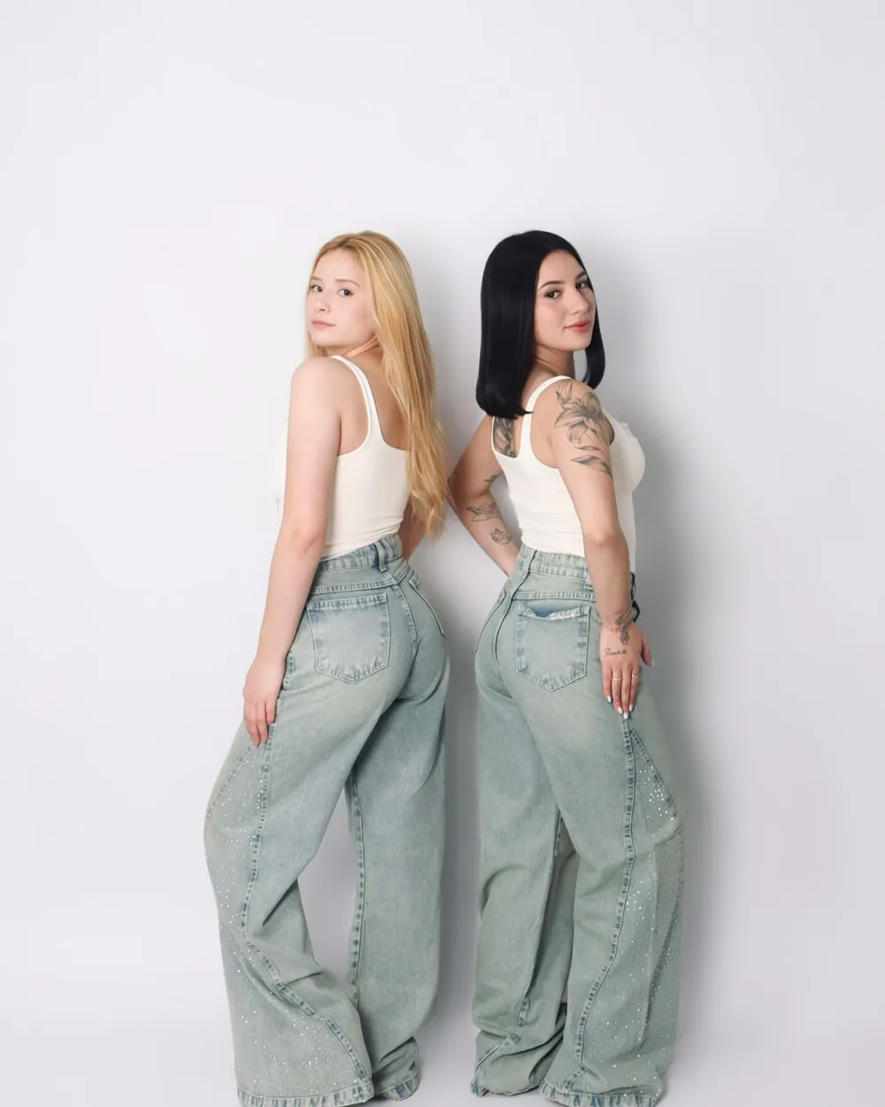 Duas modelos de costas com calças jeans wide leg